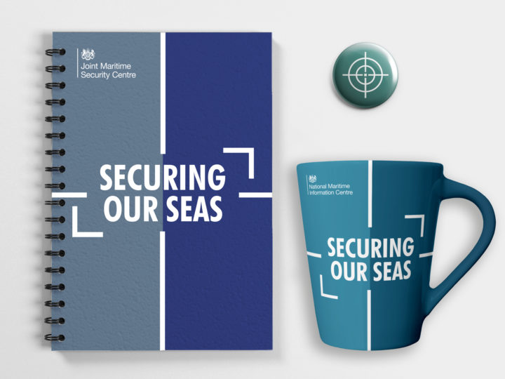 Mockups of a wire-bound notebook, mug and pin badge featuring the maritime branding. The notebook and mug have the words 'securing our seas' on them.